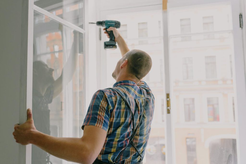 pexels-photo-5691544 Back view of worker in checkered shirt drilling window frame during renovation process in apartment